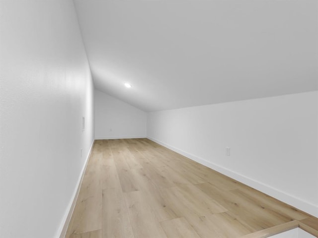 additional living space with light hardwood / wood-style flooring and lofted ceiling