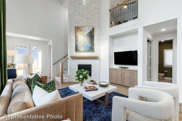 living room with a fireplace, a towering ceiling, and light hardwood / wood-style floors