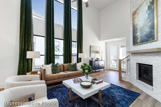 living room with hardwood / wood-style floors, a high ceiling, and a brick fireplace