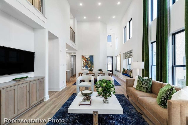 living room with a towering ceiling, light hardwood / wood-style flooring, and a wealth of natural light