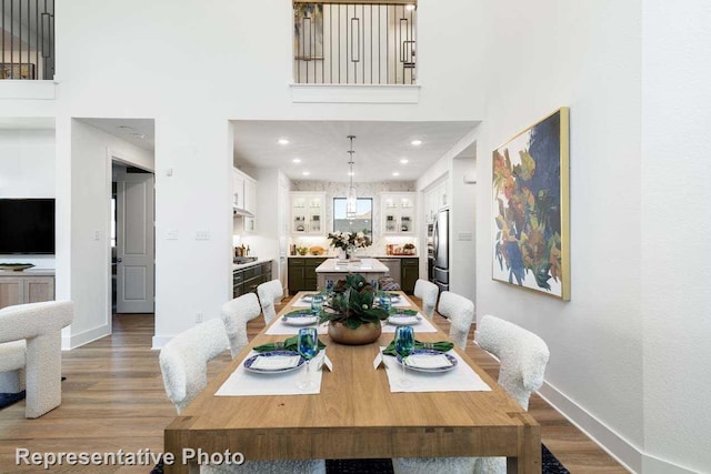 dining space with hardwood / wood-style floors and a high ceiling