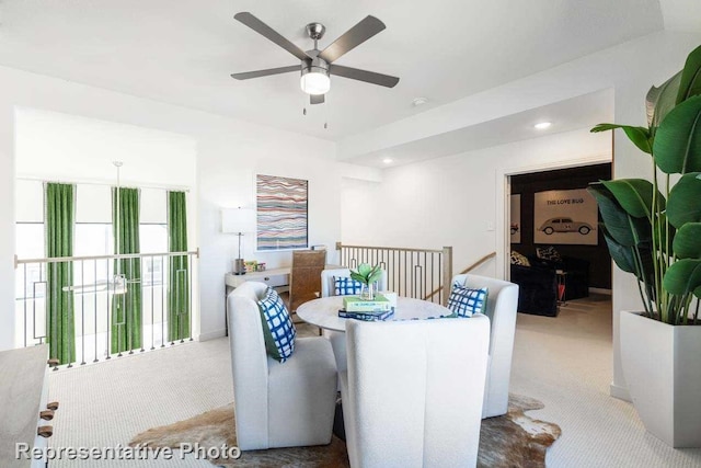 dining area with ceiling fan and light colored carpet