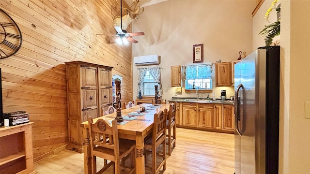 dining space with wooden walls, sink, ceiling fan, and a high ceiling