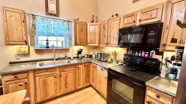 kitchen featuring sink, black appliances, and light wood-type flooring