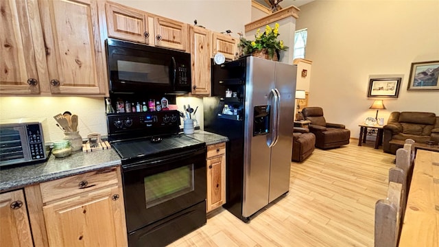 kitchen featuring light brown cabinetry, light hardwood / wood-style flooring, and black appliances