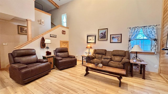 living room with a high ceiling, light wood-type flooring, and a wealth of natural light