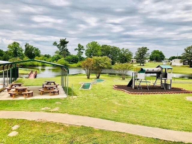 view of community with a playground, a water view, and a lawn