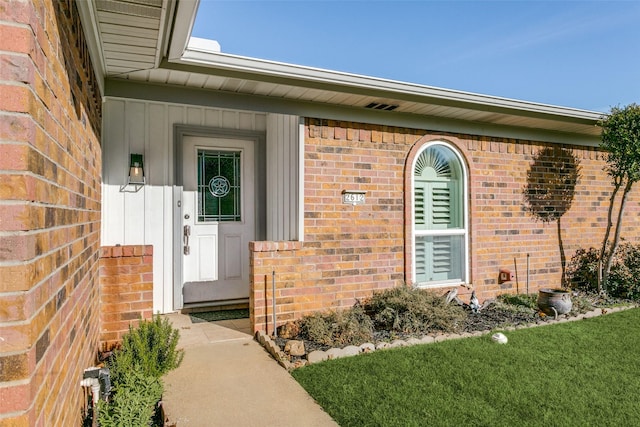 view of exterior entry featuring a lawn