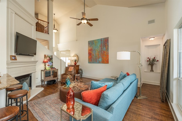 living room with high vaulted ceiling, visible vents, a fireplace with raised hearth, and a ceiling fan