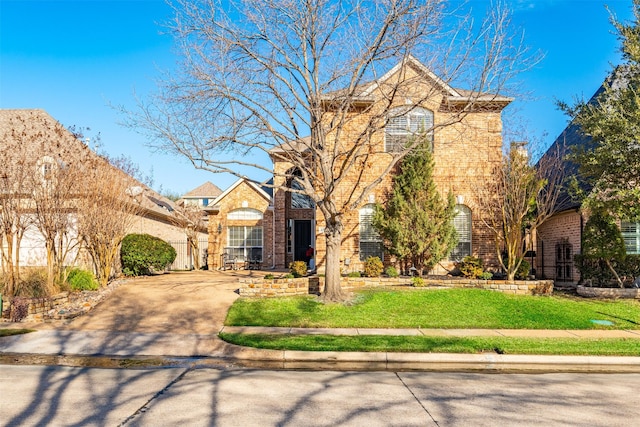 traditional-style home featuring concrete driveway, brick siding, and a front lawn