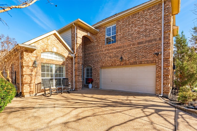 view of front of home with a garage, concrete driveway, and brick siding