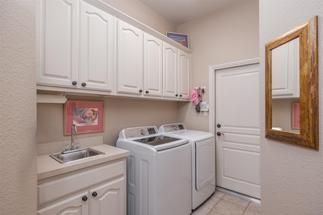 laundry area featuring cabinet space, a sink, washer and clothes dryer, and light tile patterned floors