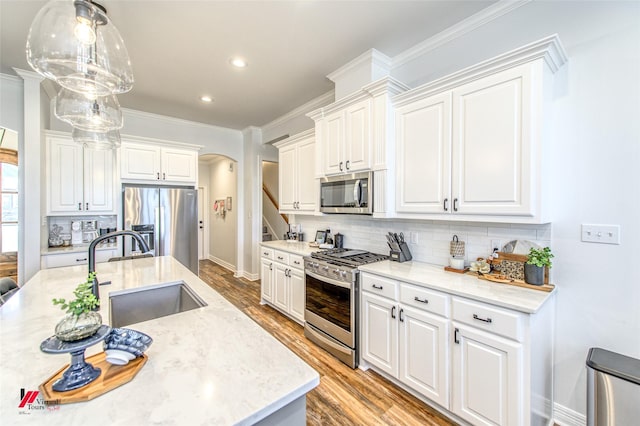 kitchen featuring appliances with stainless steel finishes, backsplash, sink, white cabinets, and hanging light fixtures