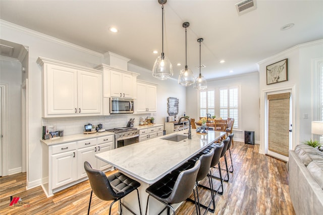 kitchen with a kitchen bar, appliances with stainless steel finishes, a center island with sink, and sink