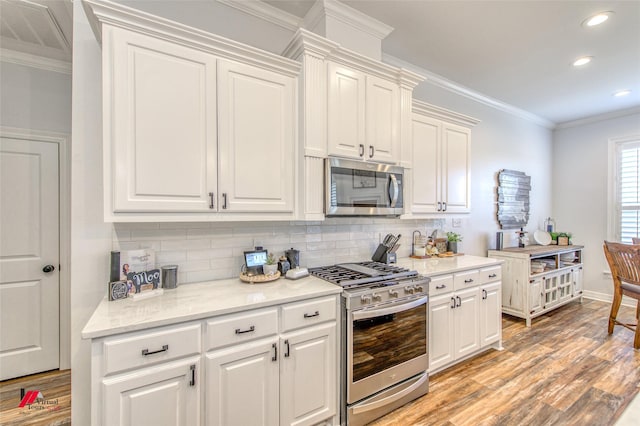 kitchen featuring white cabinetry, light hardwood / wood-style flooring, stainless steel appliances, and ornamental molding