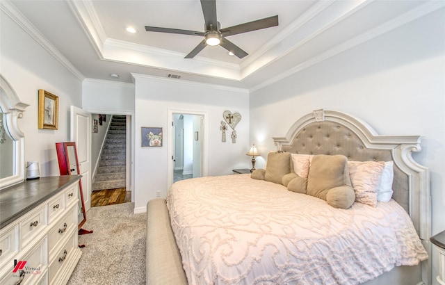 bedroom with a tray ceiling, ceiling fan, light colored carpet, and ornamental molding