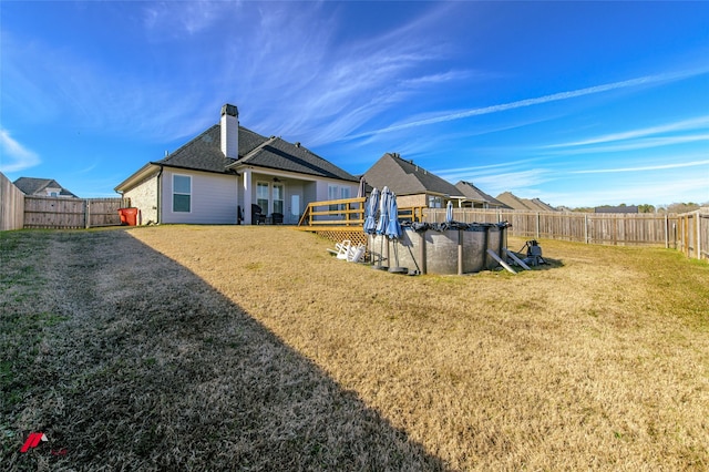 back of property featuring a yard and a covered pool