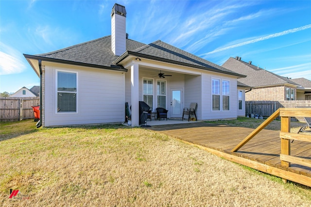 rear view of property featuring a lawn, ceiling fan, and a deck