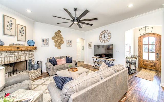 living room with a fireplace, hardwood / wood-style floors, ceiling fan, and ornamental molding