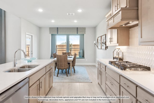 kitchen featuring backsplash, stainless steel appliances, sink, light brown cabinets, and light hardwood / wood-style floors