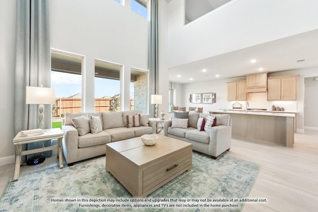 living room with a healthy amount of sunlight, light wood-type flooring, and a high ceiling