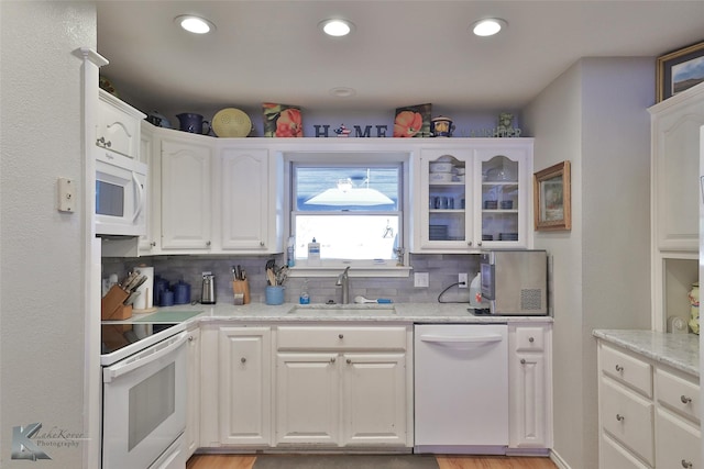 kitchen with sink, light stone counters, backsplash, white appliances, and white cabinets