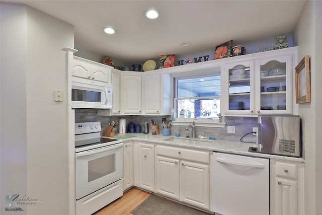 kitchen featuring white appliances, sink, tasteful backsplash, light hardwood / wood-style floors, and white cabinetry