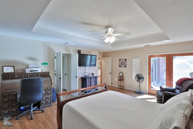 bedroom featuring light hardwood / wood-style flooring, a raised ceiling, and ceiling fan