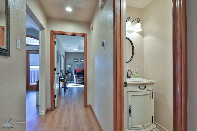 corridor featuring light hardwood / wood-style flooring and sink