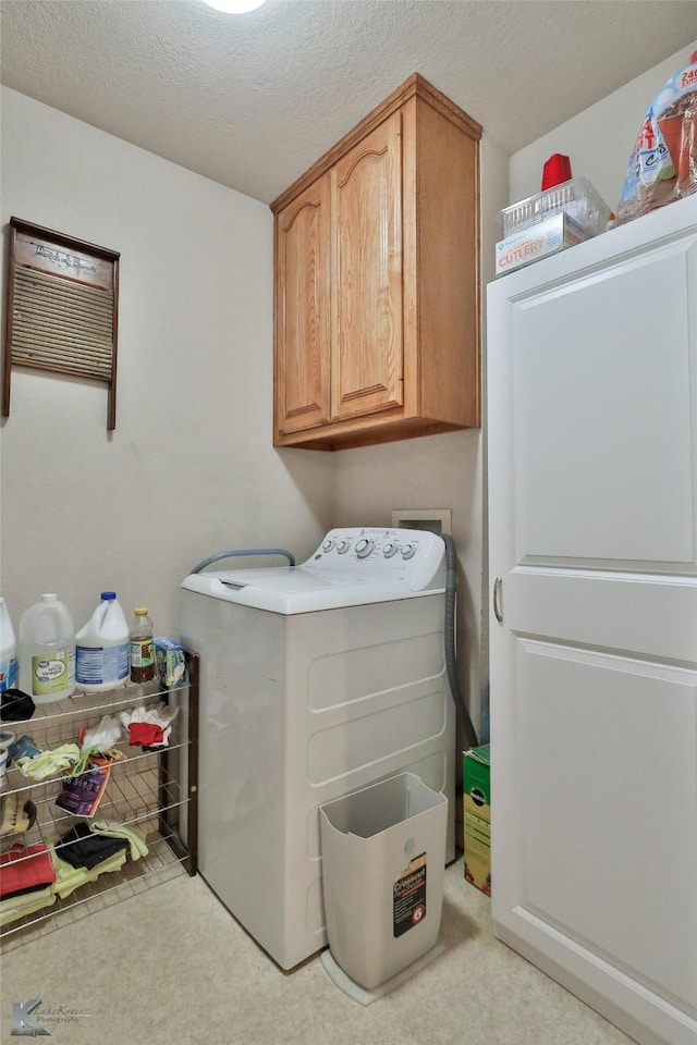 laundry area with separate washer and dryer, cabinets, and a textured ceiling