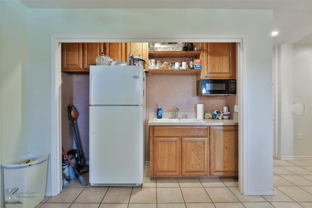 kitchen featuring white fridge, light tile patterned floors, and sink