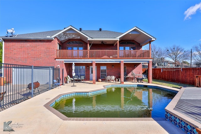 back of property with a fenced in pool, ceiling fan, a balcony, and a patio