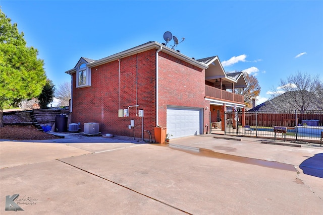 back of house with a balcony, a garage, and central air condition unit