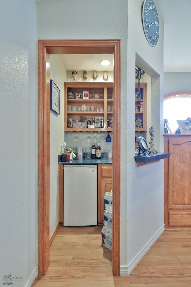 bar with light hardwood / wood-style flooring, refrigerator, and white dishwasher