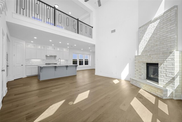 kitchen with an island with sink, backsplash, pendant lighting, and white cabinetry