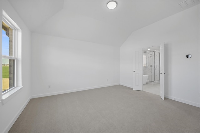 carpeted spare room featuring vaulted ceiling, visible vents, and baseboards