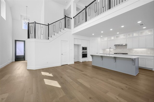 living room featuring a towering ceiling, a fireplace, and light hardwood / wood-style flooring