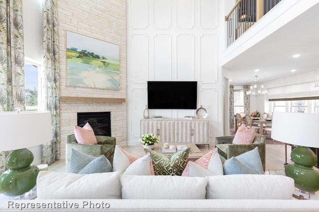 living room with a high ceiling, a fireplace, light hardwood / wood-style flooring, and a chandelier