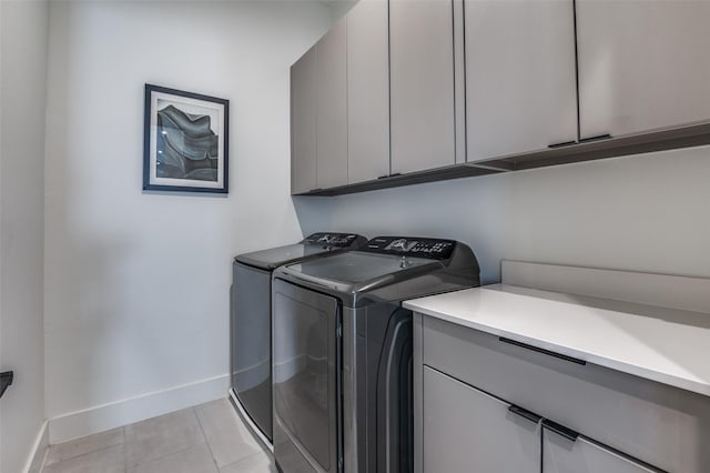 laundry room with light tile patterned floors, washing machine and clothes dryer, and cabinets