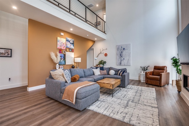 living room with hardwood / wood-style floors and a towering ceiling