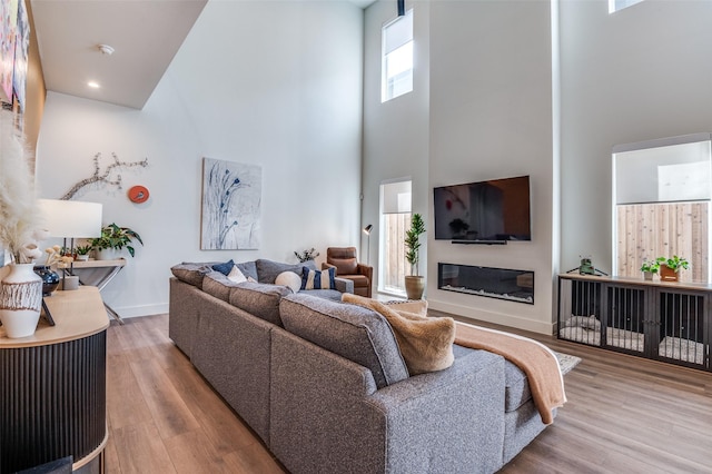 living room with light wood-type flooring and a towering ceiling