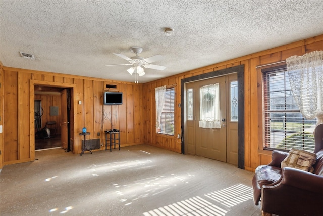 foyer entrance featuring wooden walls, ceiling fan, and a healthy amount of sunlight