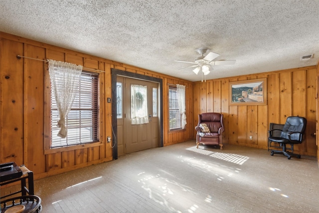 sitting room with wooden walls and ceiling fan