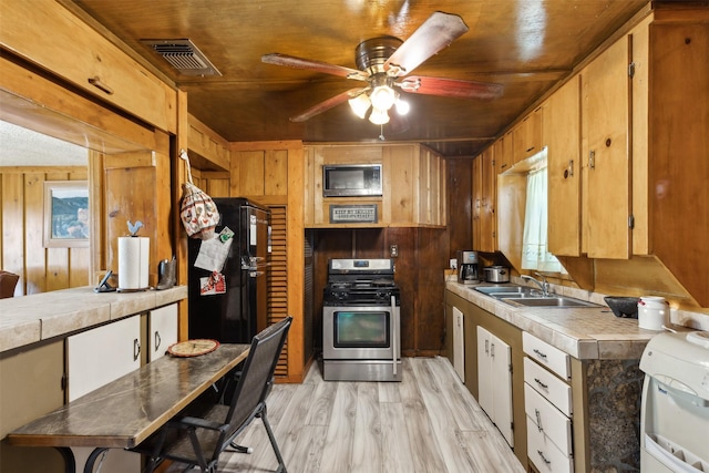 kitchen featuring black refrigerator, stainless steel range with gas cooktop, wooden ceiling, and sink