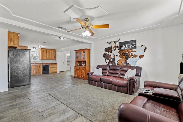 living room featuring light wood-type flooring, ceiling fan, and sink