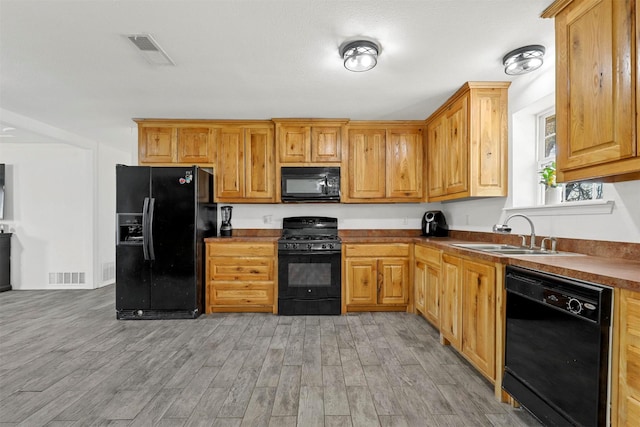 kitchen with black appliances, sink, and light hardwood / wood-style flooring