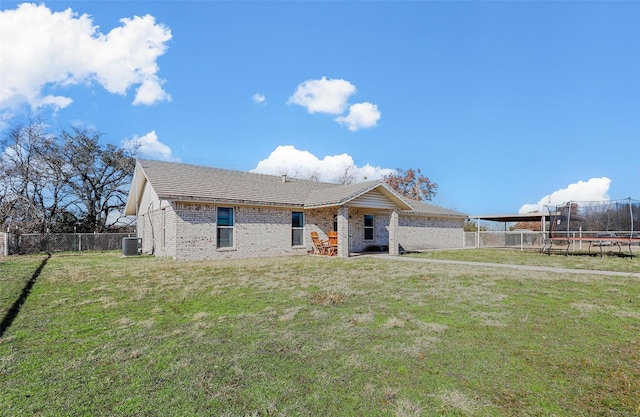 view of front facade featuring a front lawn, a trampoline, and central AC