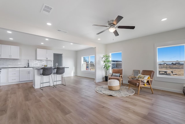 sitting room with ceiling fan, light hardwood / wood-style flooring, a healthy amount of sunlight, and sink