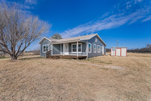 view of front facade with covered porch, a storage unit, and a front yard