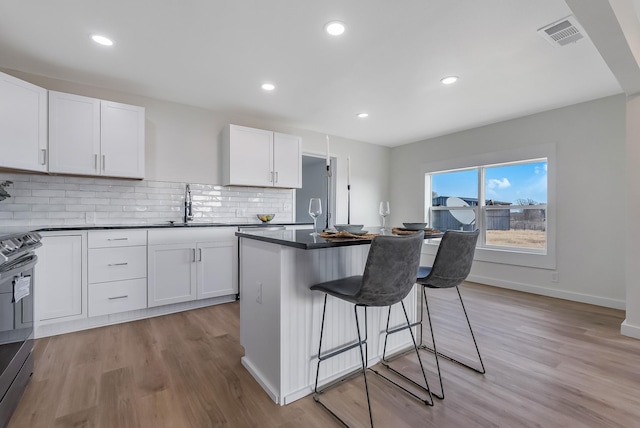 kitchen with a center island, sink, a breakfast bar area, decorative backsplash, and white cabinets